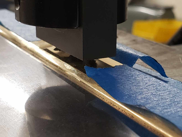 A press stamping the Battle Born Saws logo onto a brass saw back.